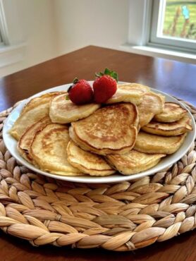 Stack of golden homemade pancakes topped with strawberries