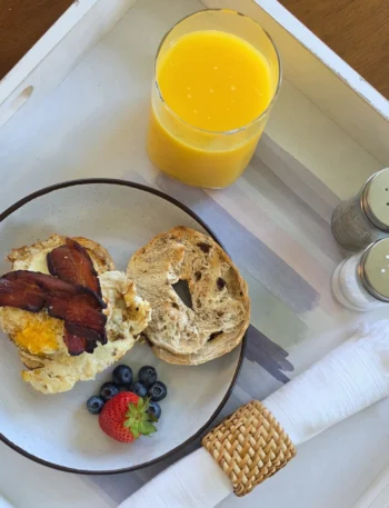 Open bacon, egg and sharp cheddar sandwich on a toasted cinnamon raisin bagel with berries and orange juice