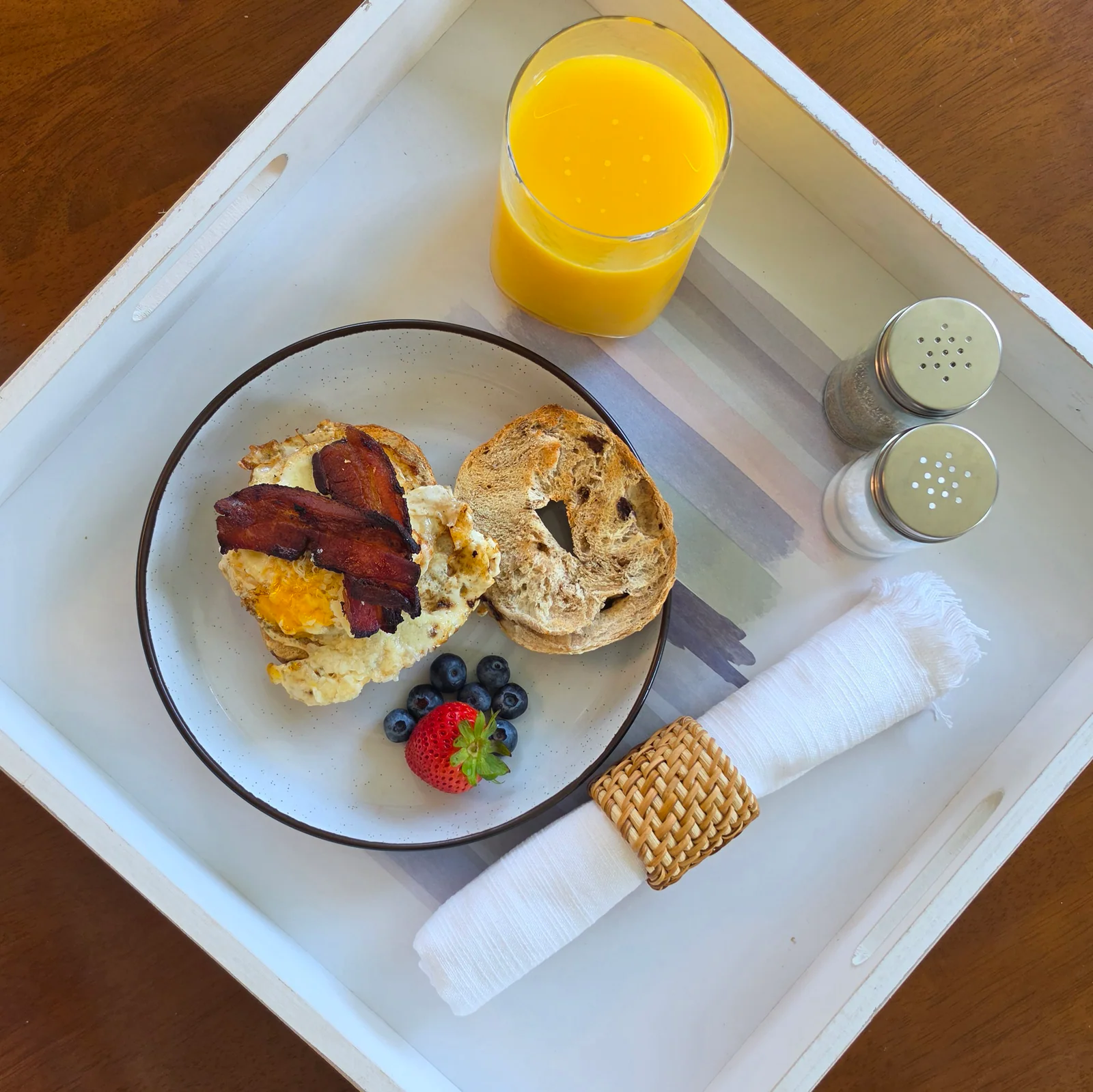Homemade bacon and egg breakfast with a bagel, berries and orange juice